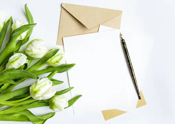 手紙、封筒と白い背景の花束。招待状、または白いチューリップと愛の手紙。平面図、平面レイアウト — ストック写真