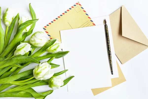 Carta, envelope e buquê sobre fundo branco. Cartões de convite, ou carta de amor com tulipas brancas. Vista superior, flat lay — Fotografia de Stock