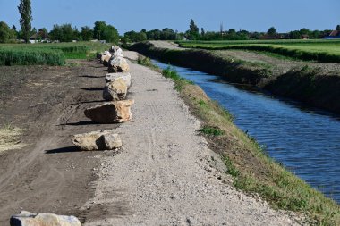 Güneşli baharda nehir kenarındaki taş sırasının resimsel görüntüsü