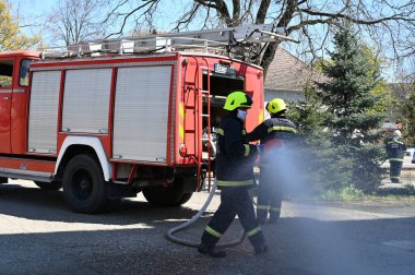Kasklı itfaiyeciler şehrin caddesinde yangın söndürüyorlar.