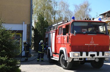 Kasklı itfaiyeciler şehrin caddesinde yangın söndürüyorlar.