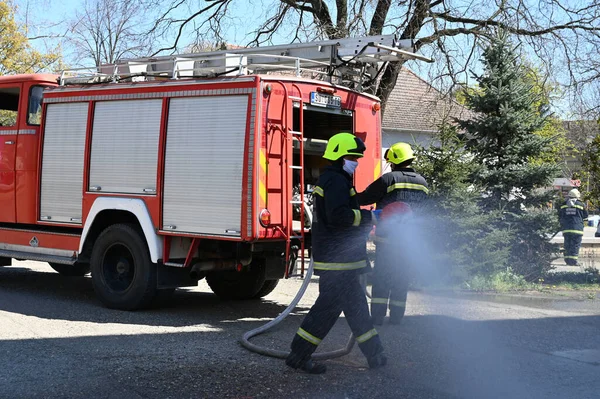 Kasklı itfaiyeciler şehrin caddesinde yangın söndürüyorlar.