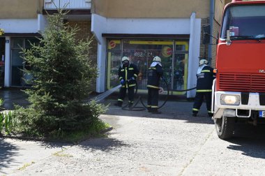 Kasklı itfaiyeciler şehrin caddesinde yangın söndürüyorlar.