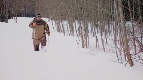 Nella foresta, un uomo sgattaiola attraverso la neve in inverno — Video Stock