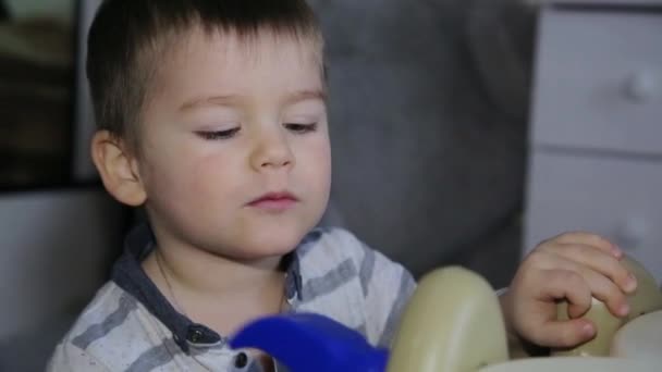 Ένα μικρό αγόρι επισκευάζει έναν πίνακα με ένα σφυρί παιχνίδι — Αρχείο Βίντεο