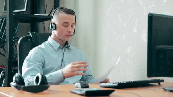 De jonge gezellige kerel de exploitant van het callcenter praten met mensen — Stockvideo