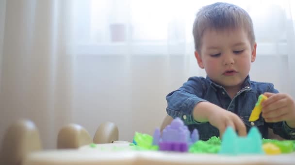 Krásný chlapeček modeluje ze zelené kinetické hrady z písku a tvarů — Stock video