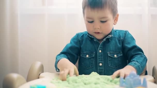 O rapaz joga com a areia cinética e desenvolve habilidades motoras de mãos — Vídeo de Stock