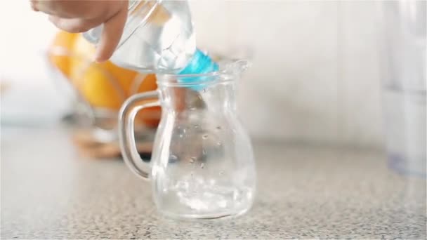 Un bambino piccolo versa da una bottiglia di plastica in una brocca di acqua potabile pulita — Video Stock