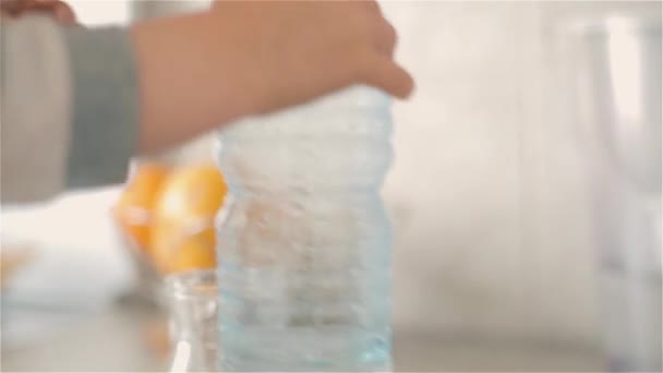 Pojken häller från en plastflaska i en kanna av rent dricksvatten — Stockvideo