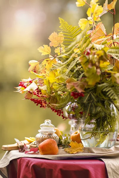 Hösten. Ett bord dukat på stranden av sjön dekorerat med en bukett höstlöv. En tebjudning. fruktte med citron, äpplen . Royaltyfria Stockbilder