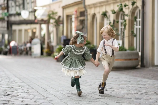 Vandrande barn på gatan.Pojken och flickan i rörelse, att springa tillsammans. Bilder i retrostil. Målare i stadens centrum.Sommartid.Tyskland Royaltyfria Stockfoton