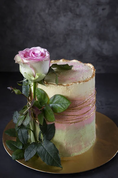Bolo caseiro O bolo de aniversário é decorado com uma rosa viva em um fundo escuro. Presentes . — Fotografia de Stock