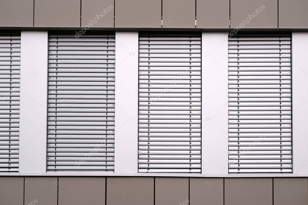 Modern metal blinds / The modern facade of an office building with window rows and metal blinds.                         