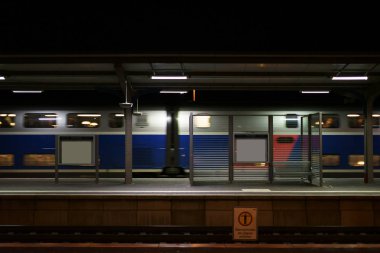 Tren geçerken ile platform / bir cam koltuklar ile gece Weinheim istasyonu platformu bölme duvar ve geçen tren.                            