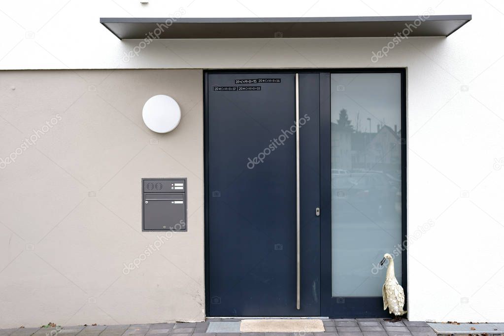 Modern house entrance / The angular and modern house entrance of a residential building with a steel door and a shelter.                          