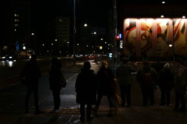 Siluetleri gece yağmurda insanlar / siluetleri geceleri arka planda soyut bir duvar resmi ile yağmurda Alexander meydanında 05 Aralık 2017 Berlin'de insanlar.                       