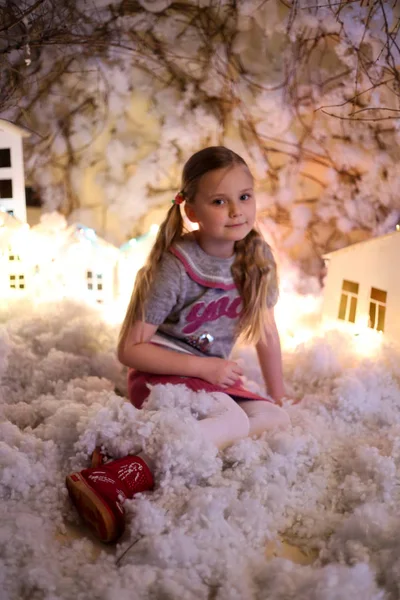 Yapay kar ve küçük mukavva evlerle Noel süslemeleri yapan kız.