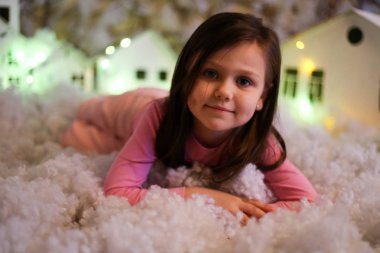 Yapay kar ve küçük mukavva evlerle Noel süslemeleri yapan kız.