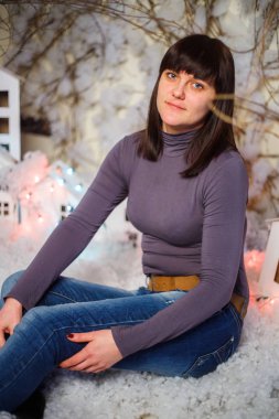 Yapay kar ve küçük mukavva evlerle süslenmiş bir kadın.