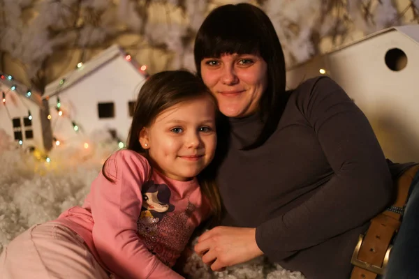 人工雪と小さな段ボールの家でクリスマスの装飾の娘を持つ母親 — ストック写真