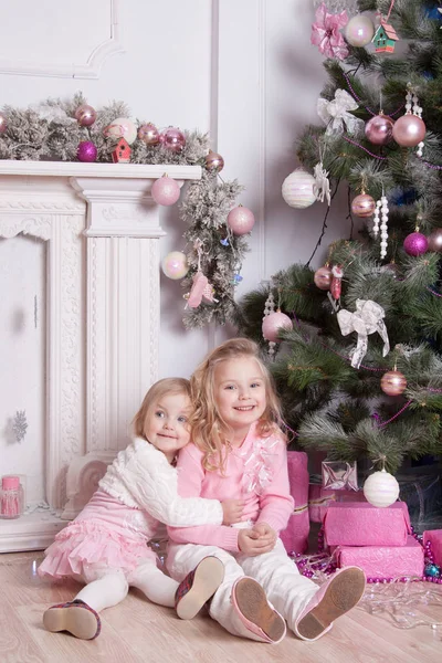 Dwie Dziewczyny Przytulają Się Śmieją Przy Kominku Drzewie Noworocznym — Zdjęcie stockowe