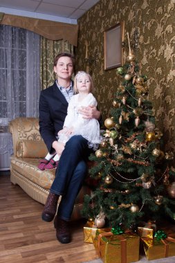 Anne ve kızı süslü Noel ağacının yanındaki kanepede oturuyorlar.