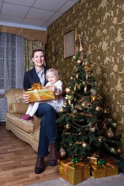 母と娘は装飾されたクリスマスツリーの近くのソファに座って — ストック写真