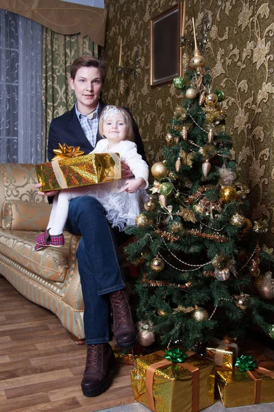 母と娘は装飾されたクリスマスツリーの近くのソファに座って — ストック写真
