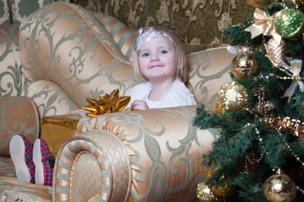 Menina Sentada Sofá Perto Uma Árvore Natal Decorada Detém Presente — Fotografia de Stock