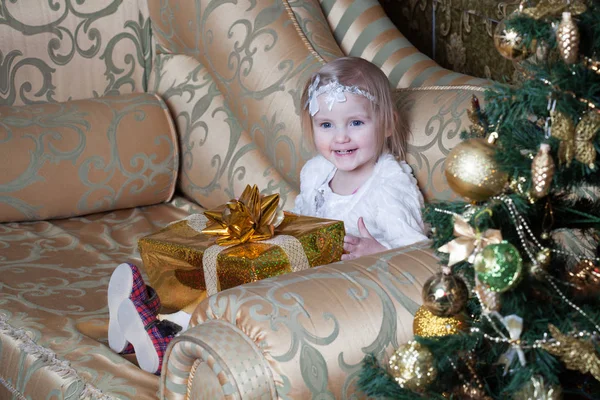 Menina Sentada Sofá Perto Uma Árvore Natal Decorada Detém Presente — Fotografia de Stock