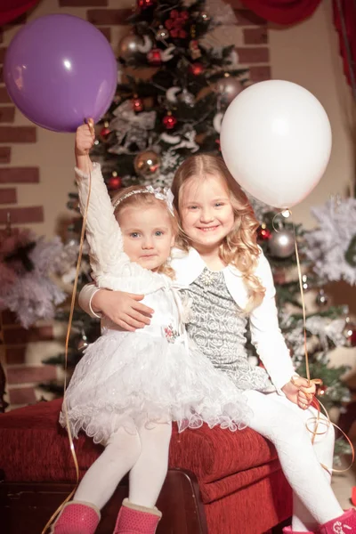 Two Girls White Purple Balloons Sitting Red Ottoman Christmas Decorations — 스톡 사진