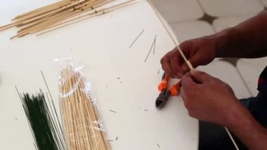 İnsan bambu çubuklarını kabloya bağlar.