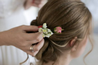 Nedime çiçekleri gelinin saçına yerleştirir.