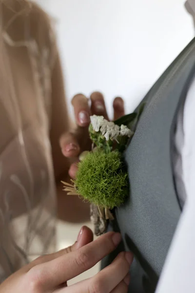 bride pins a boutonniere on the groom\'s jacket