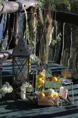 Verandayı dekoratif tezgahlarla süslemek, dekoratif lambaları mumlarla süslemek, kutuları limonlarla doldurmak.