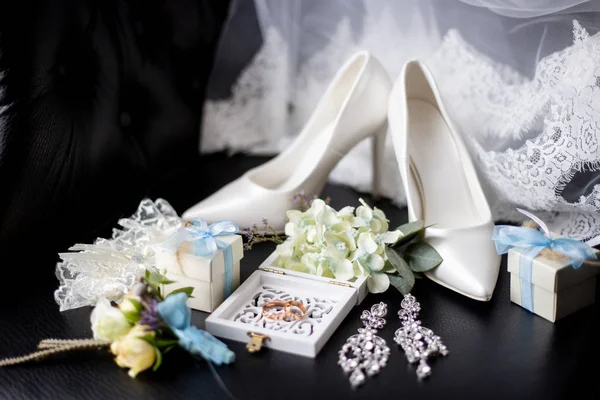 wedding accessories: wedding rings in a decorative box with flowers, earrings, women\'s shoes, a garter of the bride, a small gift, lace of a wedding dress