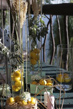 Verandayı dekoratif tezgahlarla süslemek, dekoratif lambaları mumlarla süslemek, kutuları limonlarla doldurmak.