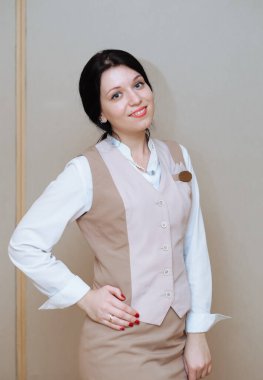 Gri arka planda bej üniformalı bir kadın.