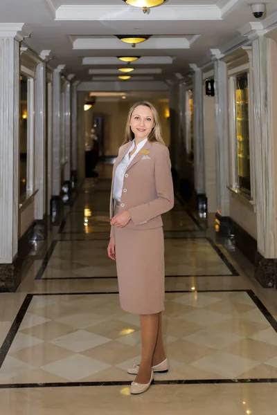 Resepsiyonist koridorda gülümseyerek ziyaretçileri selamlıyor.