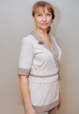 Gri arka planda beyaz kimonolu yaşlı bir kadın.