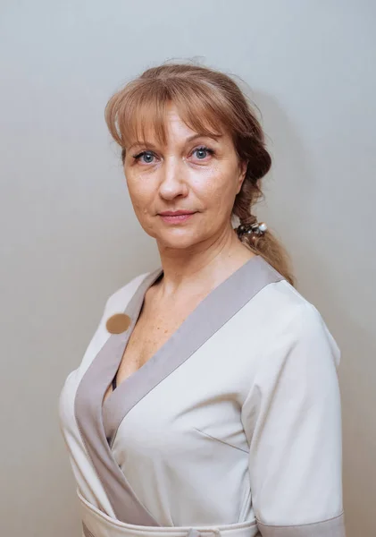 Gri arka planda beyaz kimonolu yaşlı bir kadın.