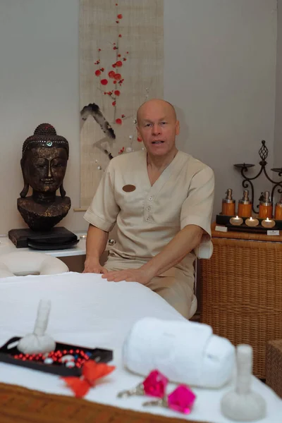masseur man sitting near massage table in massage room in asian style