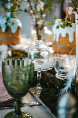 Paskalya için süslenmiş masa: Paskalya pastaları, Paskalya yumurtaları, Paskalya tavşanları, cam bardak, tabak ve bardaklarda çiçek açan kiraz dalları.