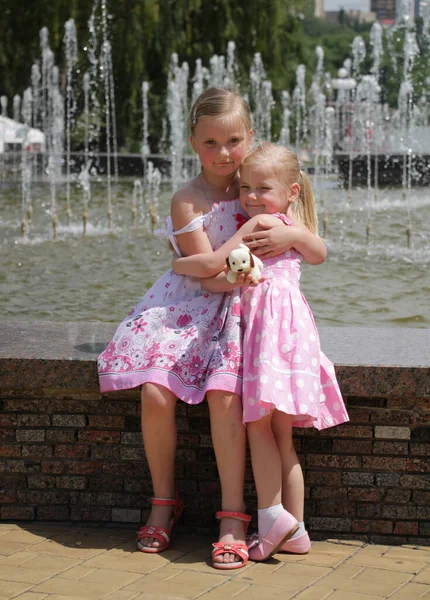 Dos Chicas Vestidos Rosa Abrazo Fuente —  Fotos de Stock