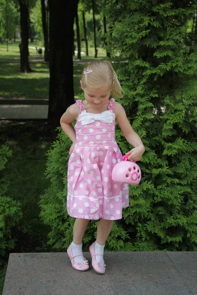 穿着粉色太阳衣的女孩站在石头上摆姿势 — 图库照片