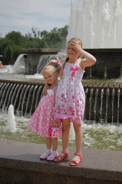 Przy Fontannie Stoją Dwie Dziewczyny Różowych Sukienkach — Zdjęcie stockowe