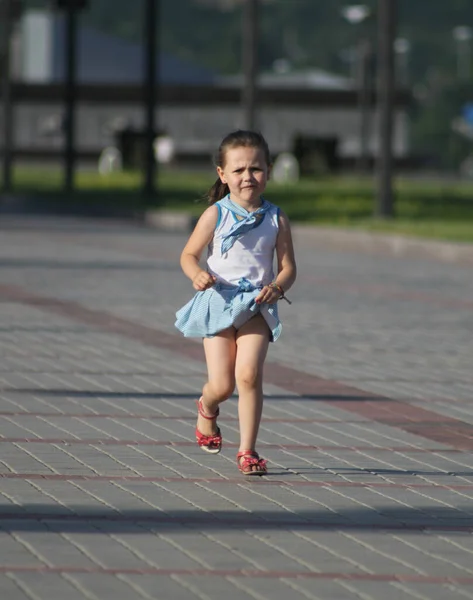 身穿蓝白相间衣服的女孩在铺路石上奔跑 — 图库照片