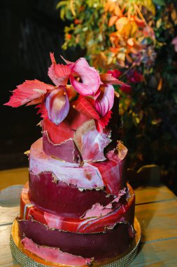 Zantedeschian çiçeğiyle süslenmiş üç katlı pasta, kırmızı yapraklar ve 