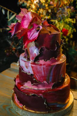 Zantedeschian çiçeğiyle süslenmiş üç katlı pasta, kırmızı yapraklar ve 